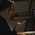 Serious young lady designer sitting indoors at night chatting