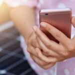 Image of faceless woman in pink dress charging her smart phone on free multipurpose solar panel charger. Modern technology, free energy for everyone, allternative electricity, ecology concept.