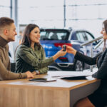 Young couple talking to a sales person in a car showroom