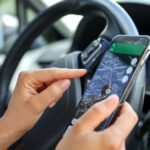 Female driver hand holding a phone with interface navigator on a screen.