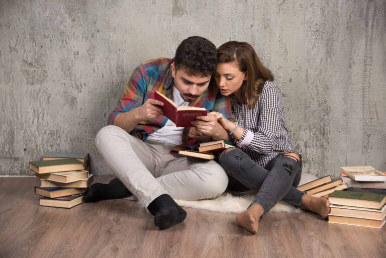 Young couple reading an interesting book while sitting on floor